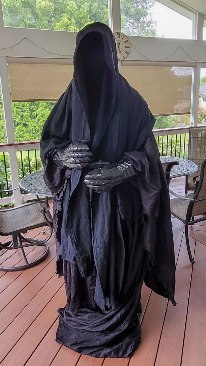 Hooded Halloween costume with skeletal gloves standing on a wooden deck, showcasing clever Halloween costume ideas.
