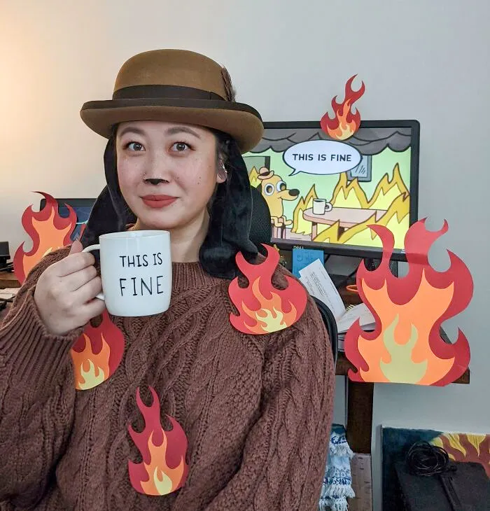 Person wearing clever Halloween costume inspired by the "This is Fine" meme holding a mug with flames around them.