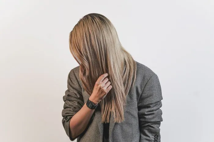 Person in a grey blazer with head down, pondering shower thoughts, against a plain background.
