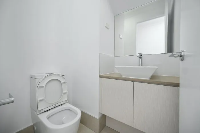 Modern bathroom with white toilet and sink, evoking shower thoughts.