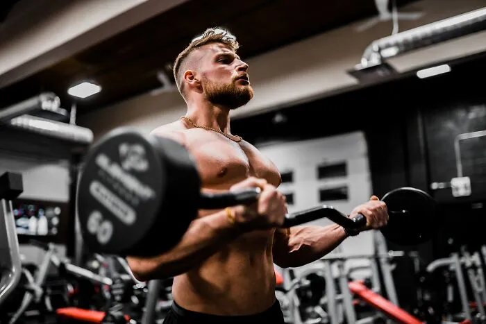 Man lifting weights in a gym, reflecting on shower thoughts and questions.