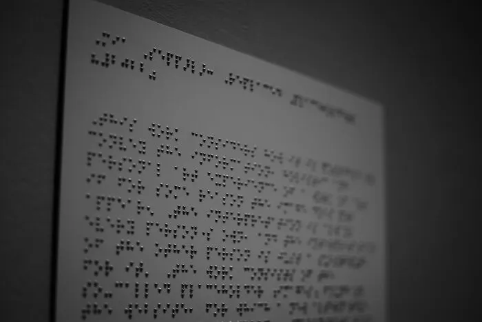 A grayscale image of a braille sheet on a wall, sparking shower thoughts questions.