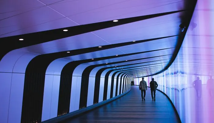 Two people walking through a futuristic tunnel, evoking shower thoughts with its abstract design.