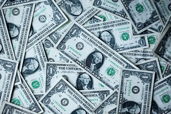 A pile of one-dollar bills spread out, possibly sparking shower thoughts about money and value.