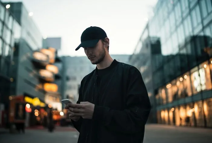 Man with a phone in an urban setting, pondering shower thoughts questions.