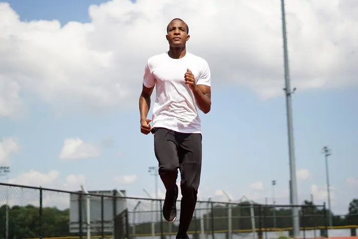 Man running on a track under a cloudy sky, capturing a moment for shower thoughts questions contemplation.