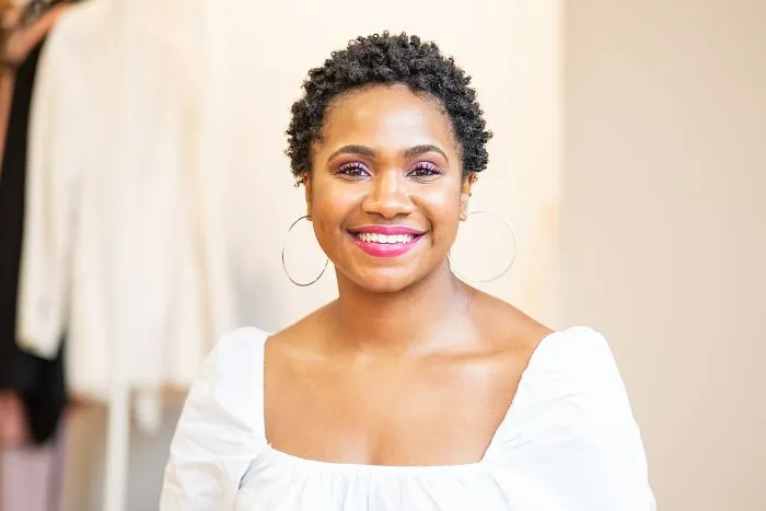 Smiling person in a white shirt, conveying thoughts in a bright setting, related to shower thoughts questions.