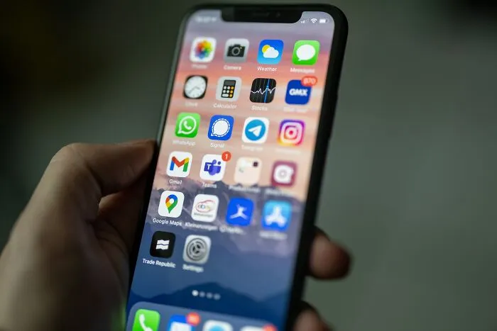 Person holding a smartphone displaying various apps, sparking thoughts and questions.