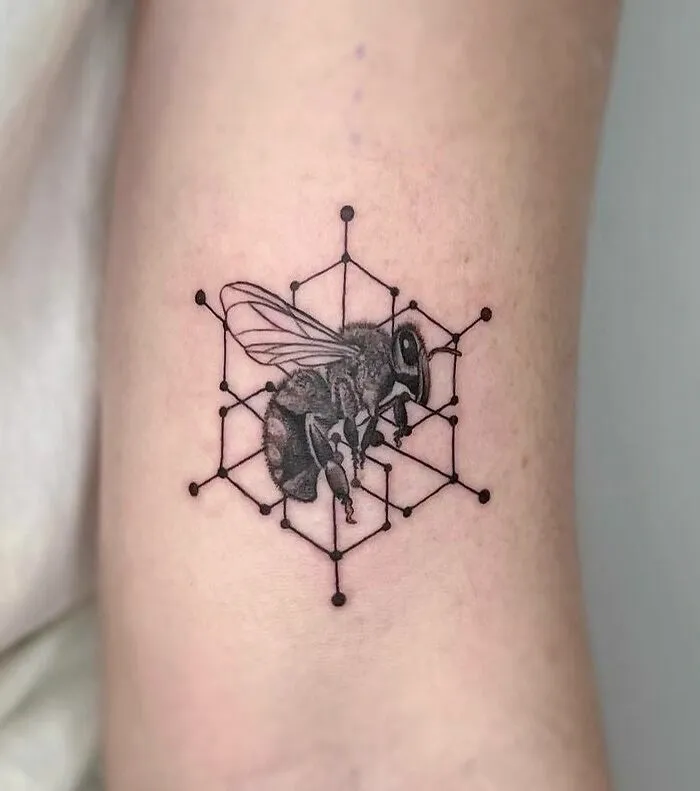 Bee tattoo with geometric hexagon shapes on arm, highlighting creativity and forms in geometric tattoo design.