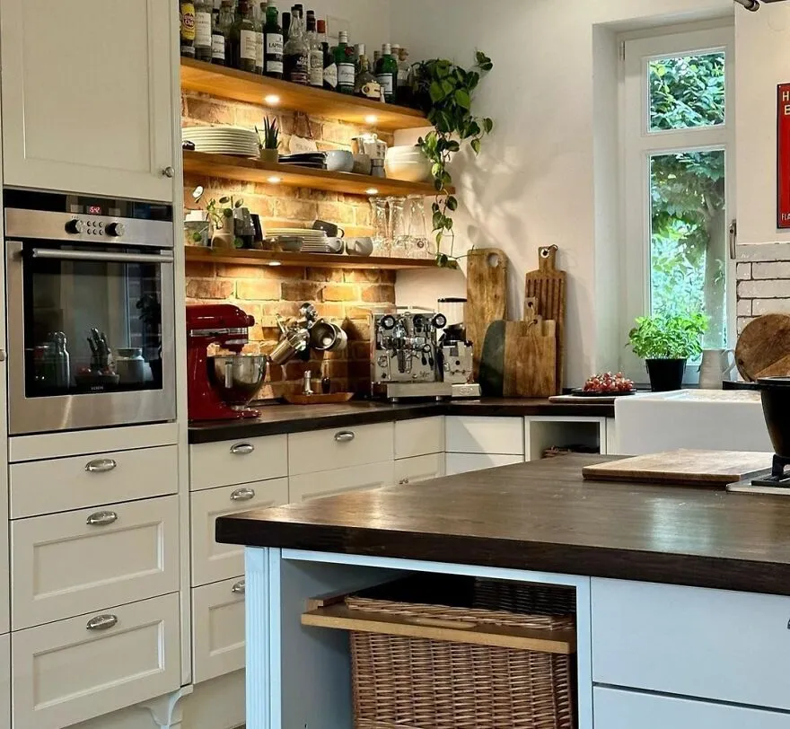 Wooden open shelves with kitchen items above modern and stylish kitchen cabinets in a bright, cozy kitchen space