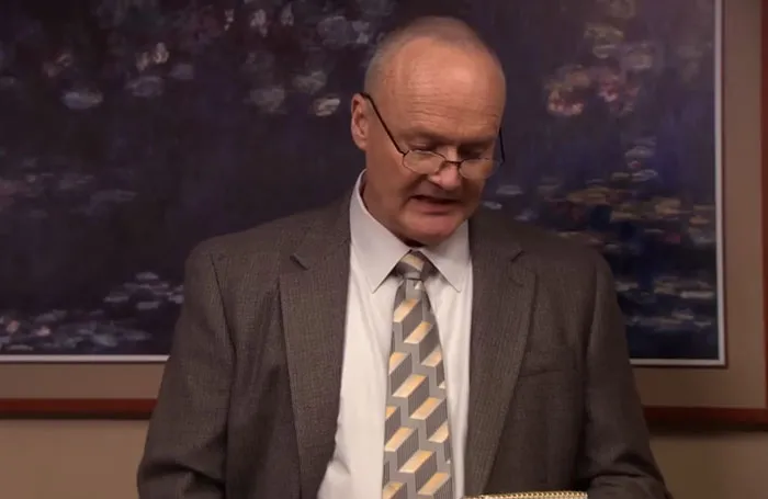 Creed Bratton reading a presentation to colleagues