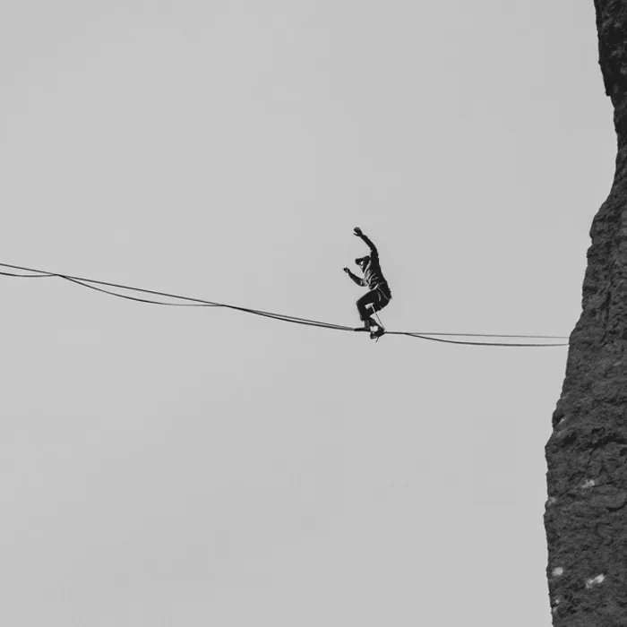 Man walking on a tightrope between cliffs performing one of the weirdest Guinness World Records challenges.