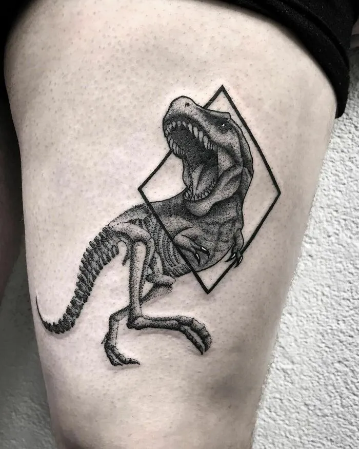 Dinosaur tattoo on a thigh featuring a roaring T-Rex in a geometric design, executed with intricate detail.