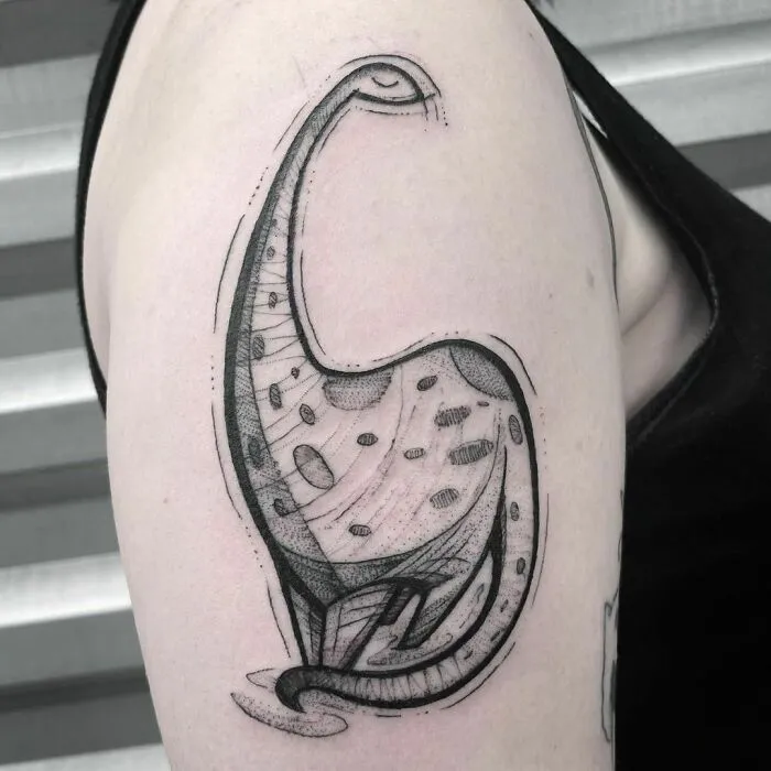 Minimalist dinosaur tattoo on a person's upper arm, featuring a unique dotwork and line art style.