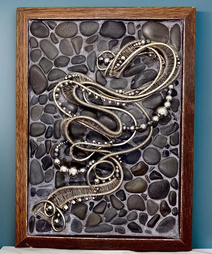 Framed vintage jewelry art displayed on a textured stone background, showcasing creative wall art ideas for a stylish space.