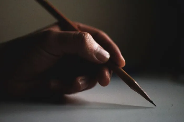 Man holding yellow pencil, symbolizing challenge and creativity while tackling hard riddles.