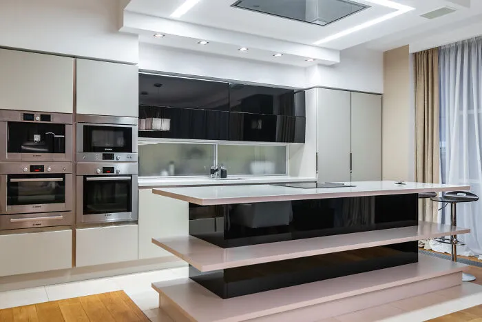 Modern and stylish kitchen cabinets with a black and white long island in the center of a sleek, contemporary kitchen design