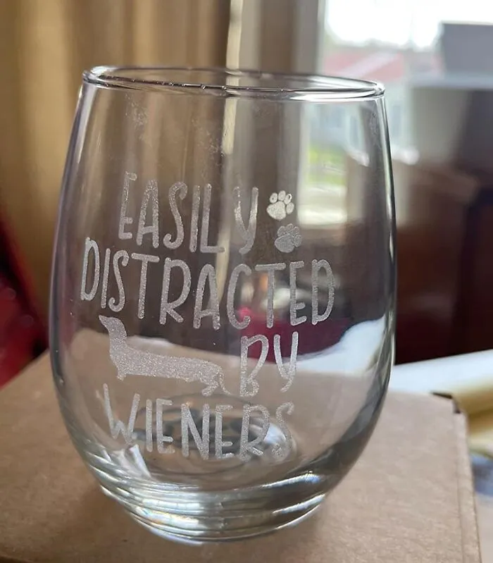 Glass with "Easily Distracted by Wieners" text, featuring a dachshund graphic, adding humor to products.