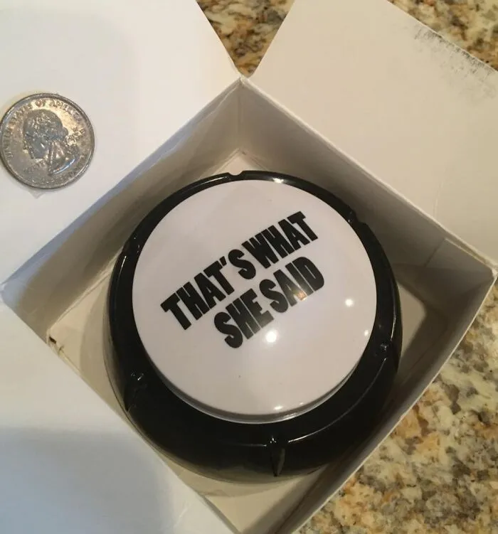 "That's What She Said button in a box, sitting next to a quarter, showcasing funny products."