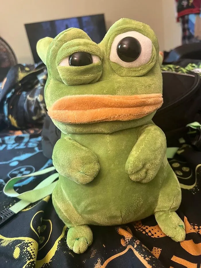 Quirky plush frog toy with large eyes on a colorful bedspread, showing a funny expression.