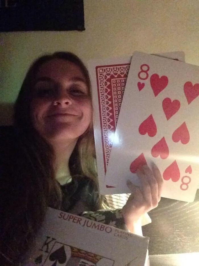 Woman holding giant playing cards, part of funny products for 2024.