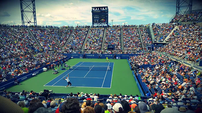People Sitting on Bench Watching Tennis Event on Field during Daytime