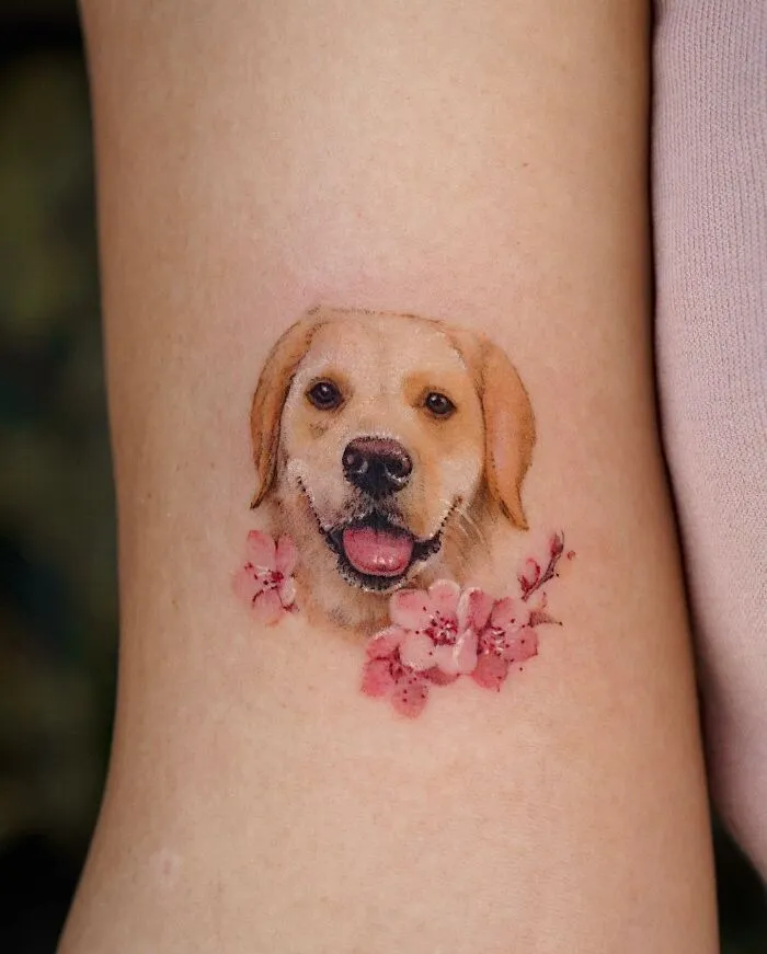 Tattoo of a dog's face with cherry blossoms, showcasing a painting-like style with nature elements.