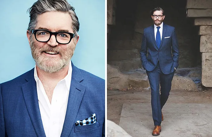 Handsome older man in blue suit and glasses, smiling confidently and walking stylishly.