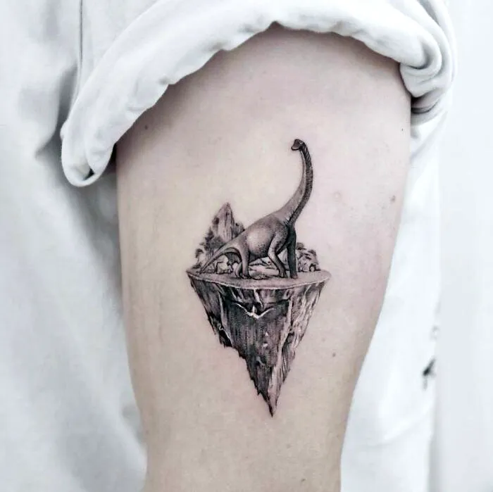 Cool dinosaur tattoo of a Brachiosaurus on a floating island, executed perfectly on an arm.