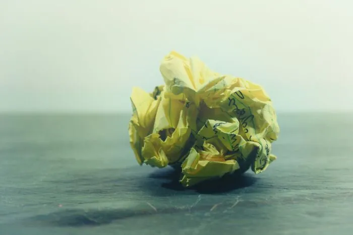 A crumpled piece of yellow paper on a desk, symbolizing discarded ideas or mistakes. Horrible resumes.