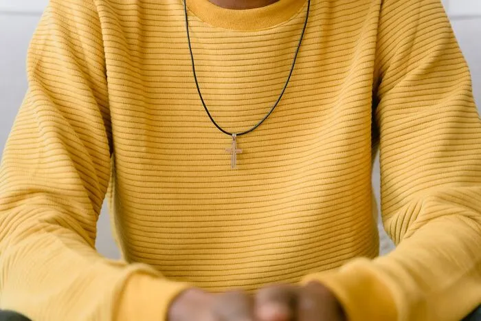 A person wearing a yellow sweater and a cross necklace, representing unique elements in resumes that went to the shredder.