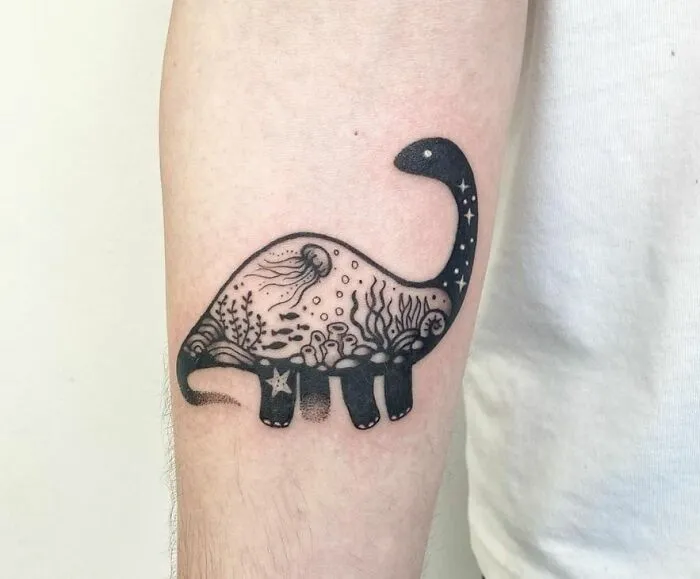 Cool dinosaur tattoo with underwater scene on a person's forearm.