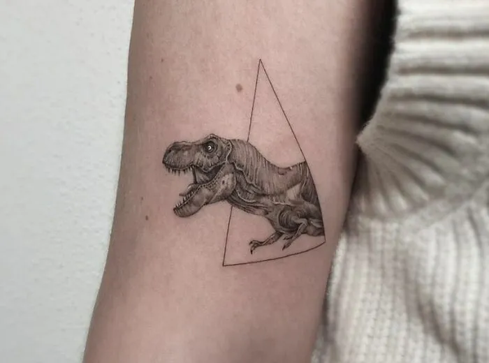 Triangular T-Rex dinosaur tattoo on arm, showcasing cool ink artistry and perfect execution.