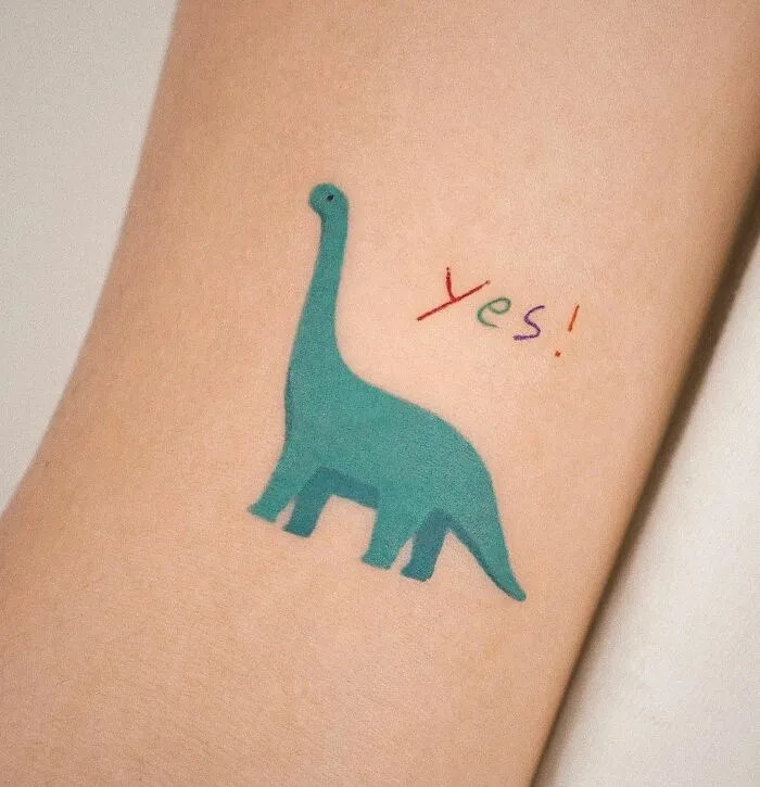 Minimalist dinosaur tattoo with colorful 'yes' text.