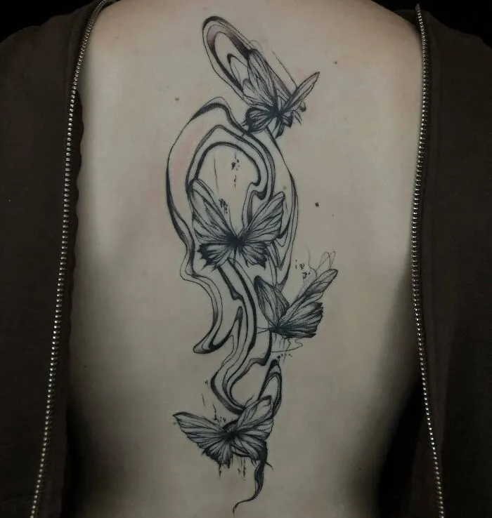 Butterfly spine tattoo with abstract design, showcasing beautiful black ink work along the back.