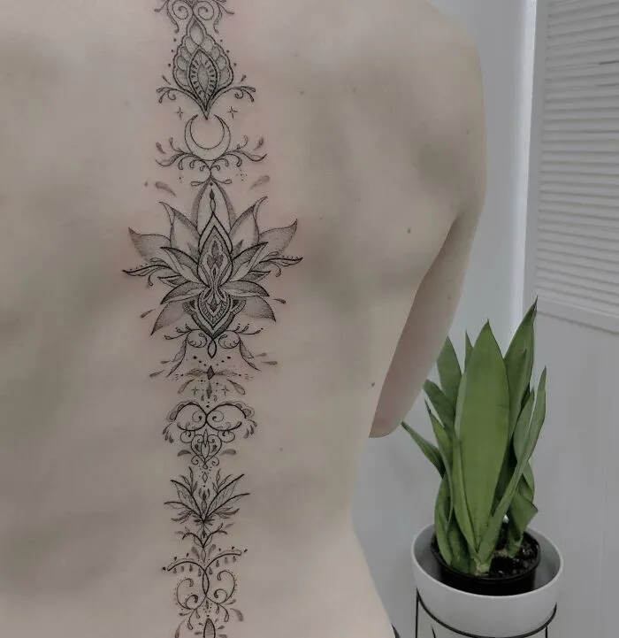 Ornate spine tattoo featuring floral and geometric designs.