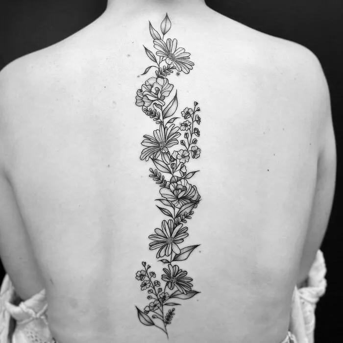 Floral spine tattoo featuring delicate linework on a woman's back.