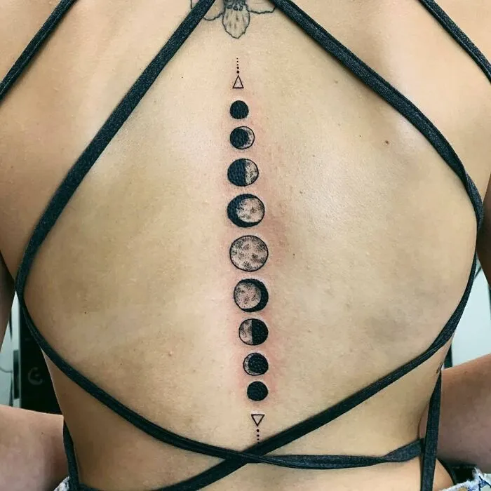 Moon phase spine tattoo with geometric lines on a person's back, showcasing beautiful spine tattoos.