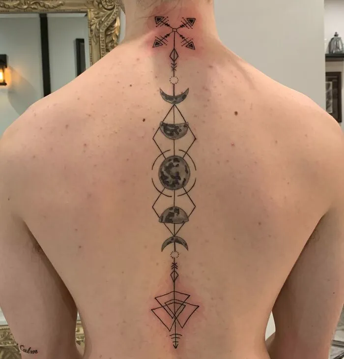 Geometric spine tattoo with moon phases on a person's back.
