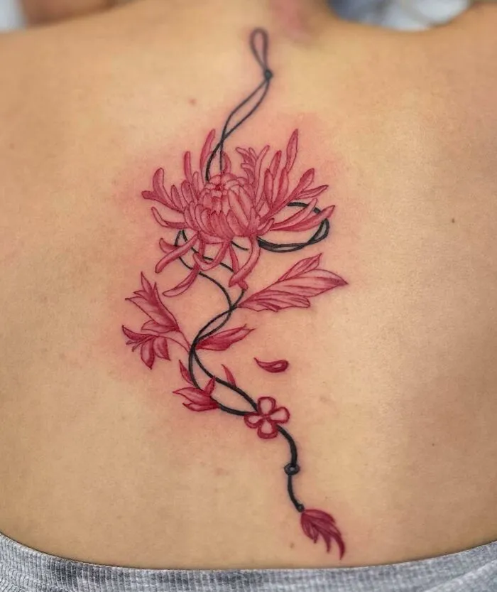 Floral spine tattoo in red and black ink with intricate design on skin.