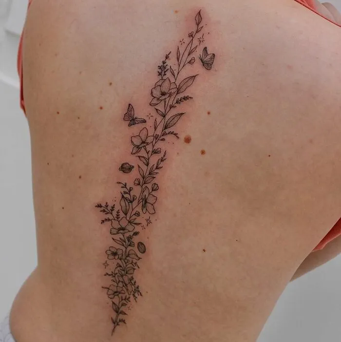 Delicate floral spine tattoo with butterflies emphasizing beauty and detail.