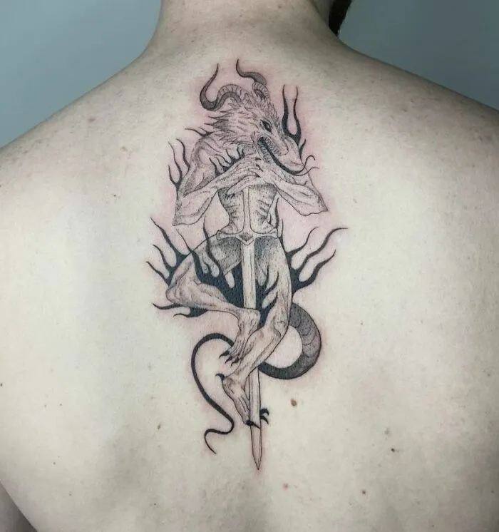 A beautifully detailed spine tattoo featuring a horned creature with flames on the back.