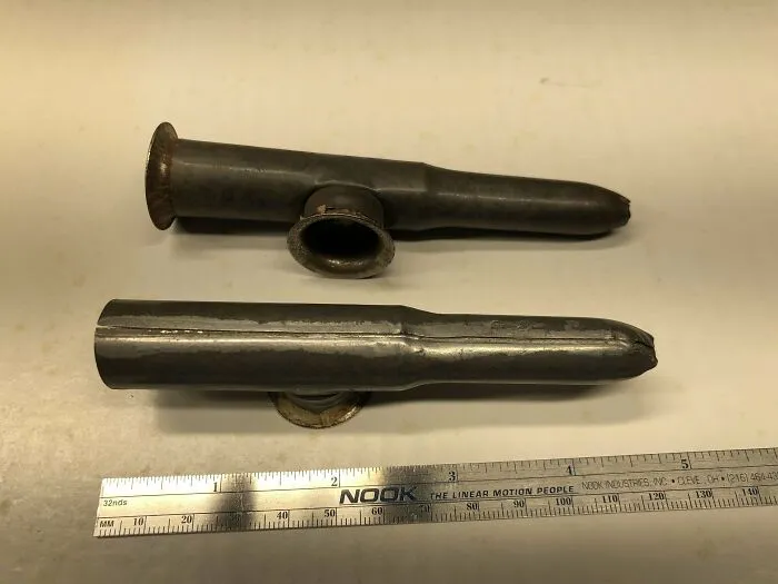 Dos pequeños objetos metálicos con tela dentro del agujero lateral.