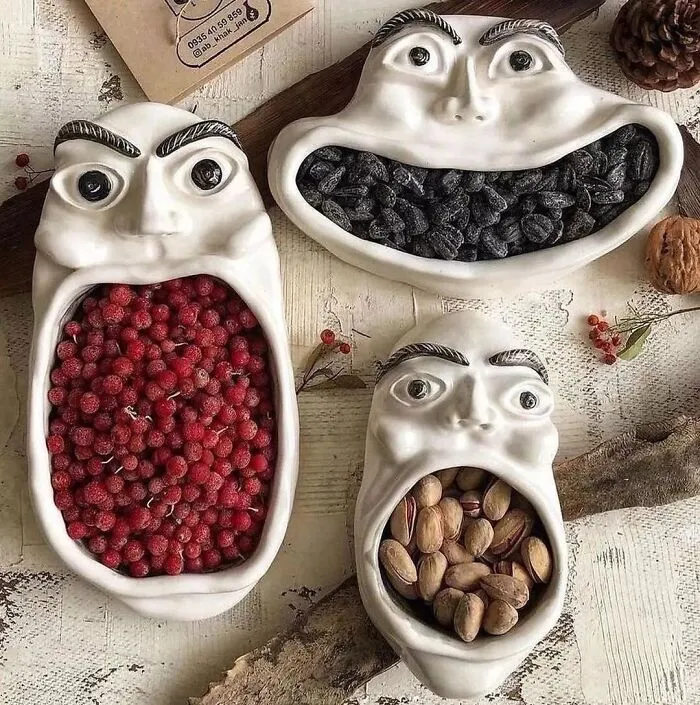 Ceramic face-shaped bowls with various nuts and berries, representing creative design from Instagram.