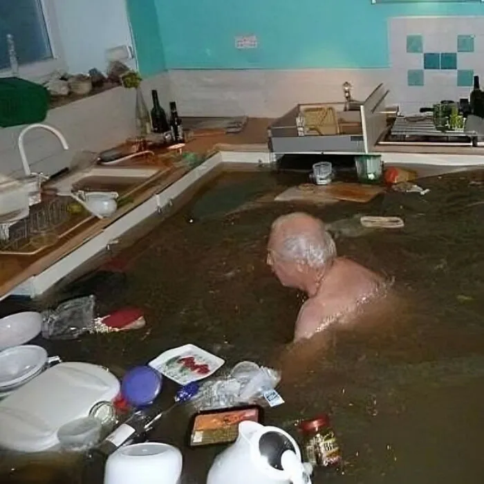 Man in a flooded kitchen surrounded by floating items, creating a surreal and cursed scene.