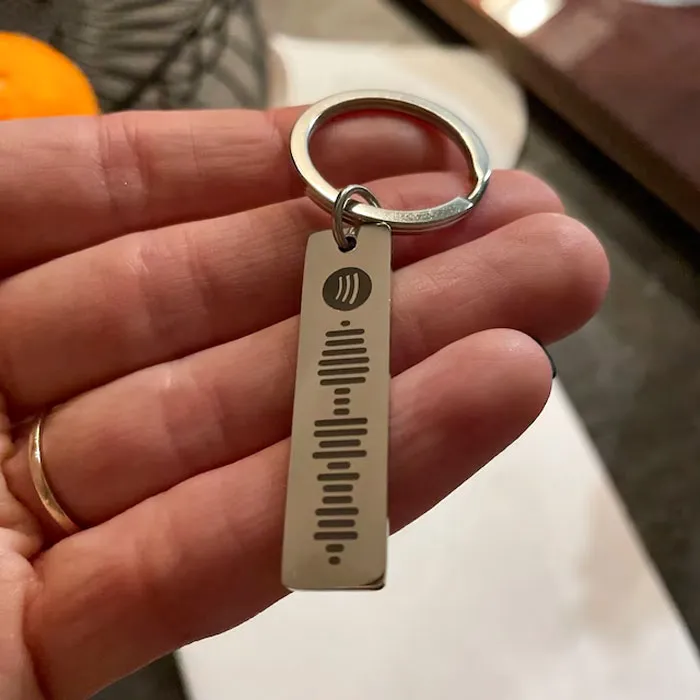 Hand holding a metal keychain with a sound wave design, perfect Valentine's Day gift under $25.