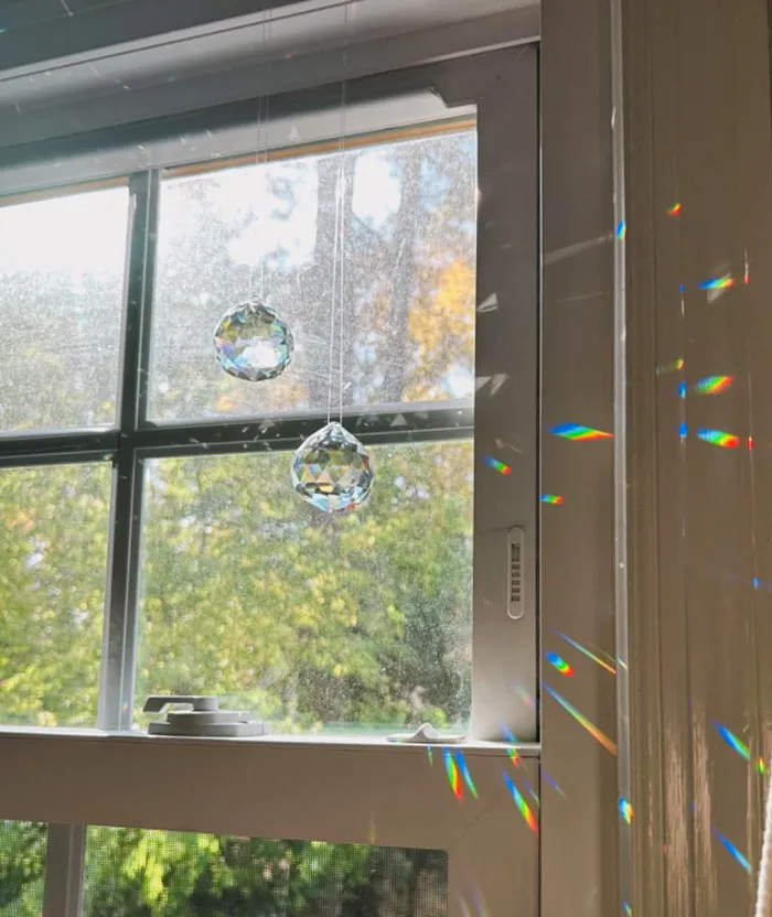 Crystal prisms hanging in a sunny window, casting colorful rainbows; an affordable Valentine's Day gift idea.
