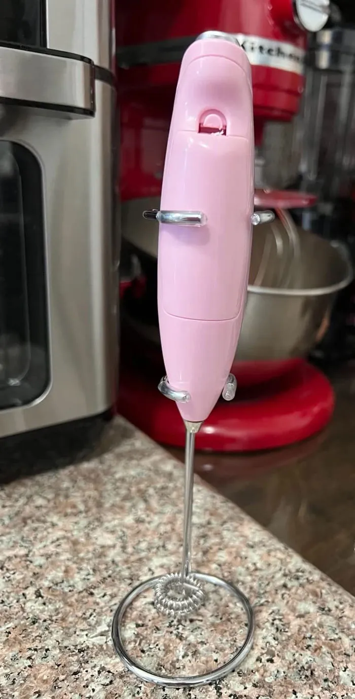 Pink handheld milk frother on a kitchen counter, ideal for affordable Valentine's Day gifts.
