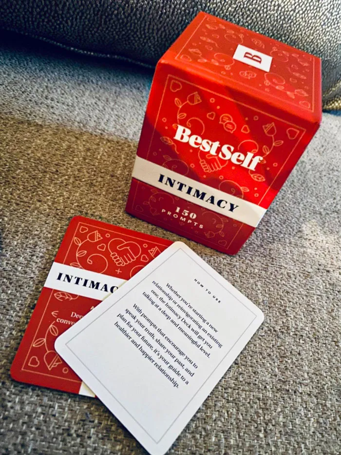 Red box of "BestSelf Intimacy" cards on a sofa, showcasing affordable Valentine's Day gift option under $25.