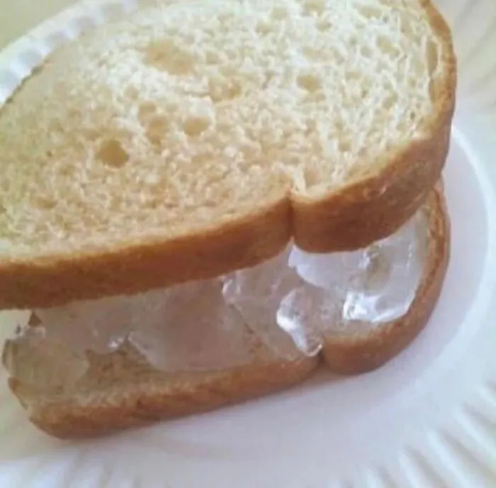 Cursed pic of an unusual sandwich made with ice cubes between slices of bread on a paper plate.